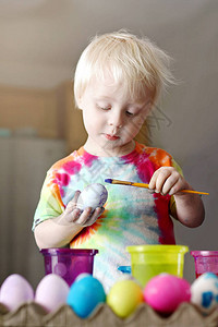 一个可爱的金发女郎2岁的小孩男正在集中精神在他家厨房里画图片