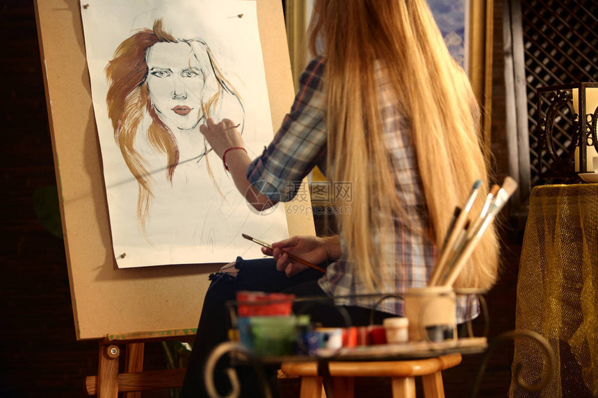 艺术家在工作室的画架上绘画女孩用画笔描绘女人的肖像从后面看到的女画家手工艺品的室内家居内饰学生作图片