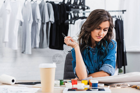 女时装设计师在服装设计工作室的工作桌上用咖啡杯背景图片