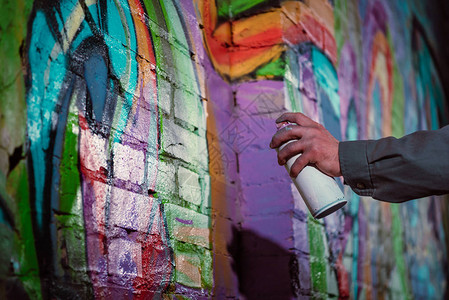 街头艺术家在夜间墙上涂喷雾的涂鸦和背景图片