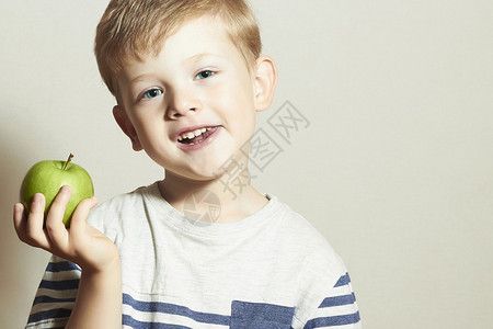 有趣的孩子吃苹果的特写肖像小英俊的男孩与青苹果健康食品水图片