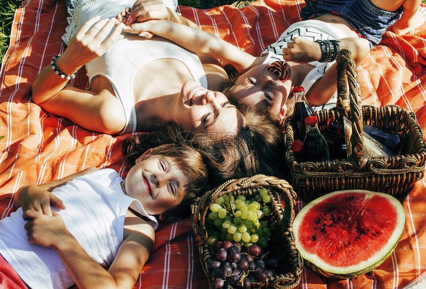 可爱的快乐家庭在野餐上躺在绿色草地上的母亲和孩子图片