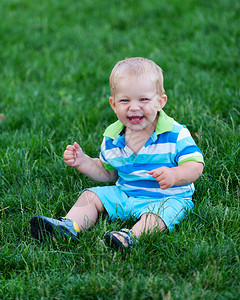 快乐的男婴坐在草地上图片