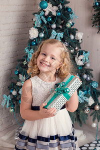 穿着白裙子的快乐小女孩在圣诞树附图片