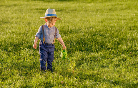 一岁的男孩在农村用水罐顶着草帽的乡村景象图片