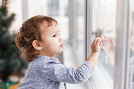 可爱的小三岁女孩透过窗户看图片