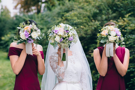 新娘和伴娘拿着白色和紫色花朵的花束图片