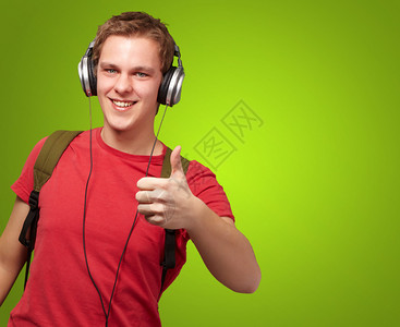 欢快的年轻学生聆听音乐和用耳机在绿色上穿戴好听图片