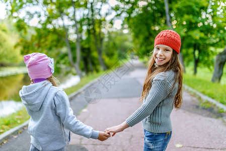 两个姐妹联手穿过秋天公园走下坡道图片