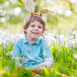 可爱快乐的孩子在春天的绿草和盛开的苹果园里戴着复活节兔子耳朵图片