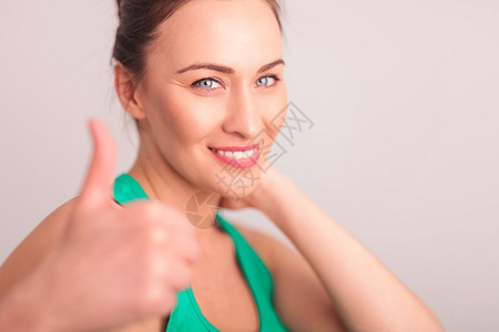 快乐的女士在摄影棚里做手拇指高举签名图片