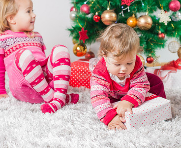 迷人的快乐孩子在地板和树上打开圣诞礼物图片