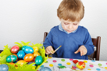 蹒跚学步的小男孩为复活节狩猎画彩蛋背景图片