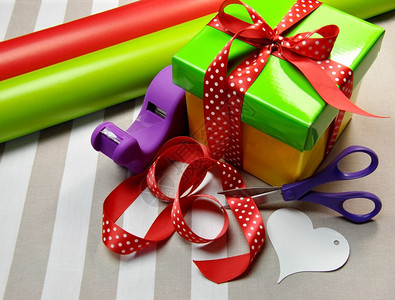 节日圣诞节生日情人节或特殊场合的明亮多彩的礼品包装场景包括礼物包装纸卷白心礼品剪刀背景图片