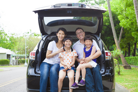 幸福的一家人坐在车里他们的房子在后面图片