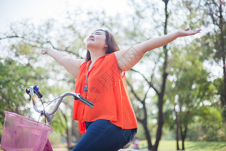 快乐胖的亚洲女人在公园户外骑自行图片