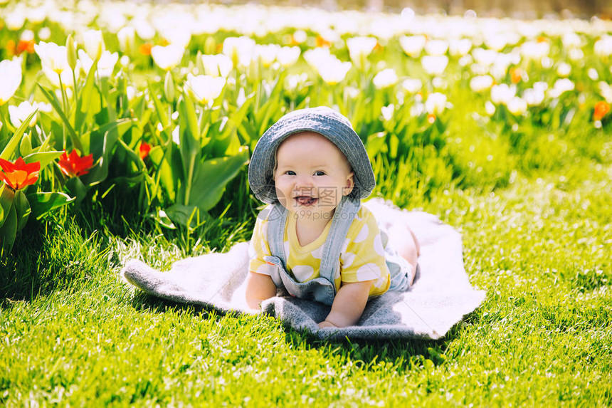 快乐微笑的女婴躺在郁金香田野绿草的毯子上孩子在春天公园户外玩耍母亲节图片