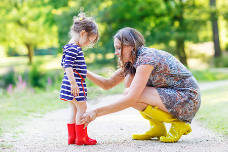 年轻母亲和可爱的小女孩穿着橡皮靴图片