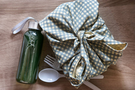 日式包布袱皮风格的健康午餐盒配绿色蔬菜和果汁瓶背景图片