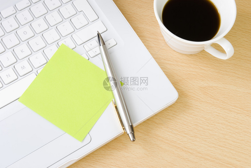 在白色笔记本电脑键盘上用一杯咖啡安排的图片