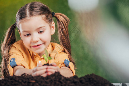 以模糊的背景地球日概念为背景种植幼苗的儿童有图片