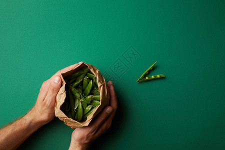 男子手持纸袋与绿色表面豌豆荚的短片图片