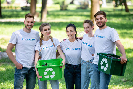 青年志愿者带着绿色回收箱为站在公园的图片