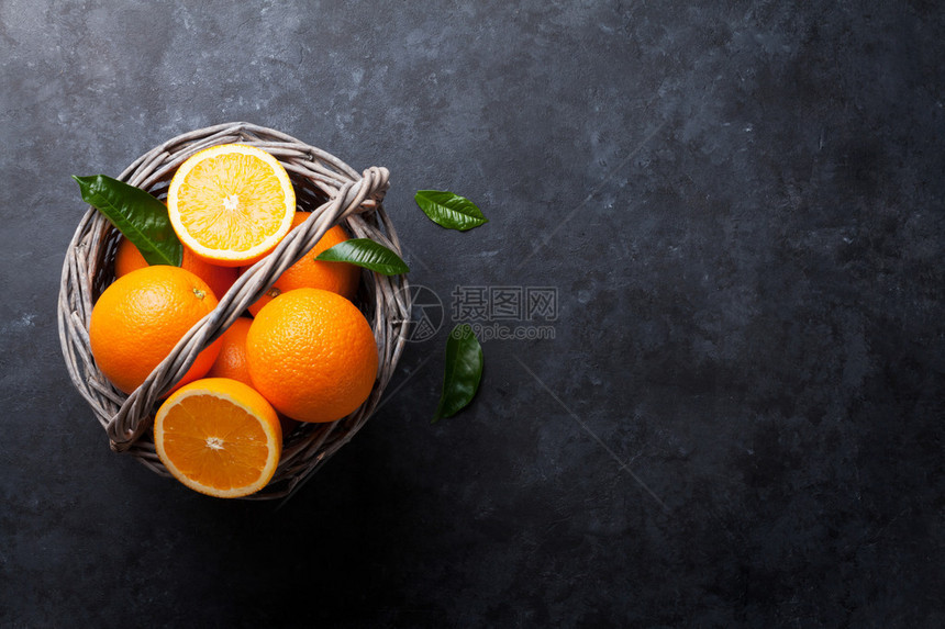 将新鲜橙子水果放在石板上的篮子中图片