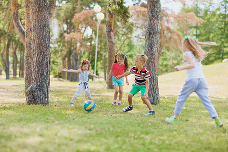 一群友好的孩子在绿色草坪上玩球图片