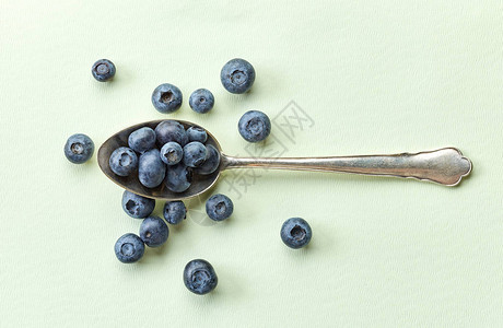 蓝莓用旧银勺装在浅绿纸背图片