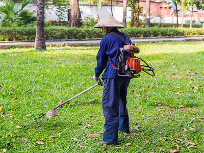 花园的工人在剪草穿着普通工人制服的男人在草坪上工作改善地区的图片