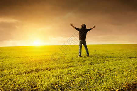 人在一个绿色的田野里举起手来图片
