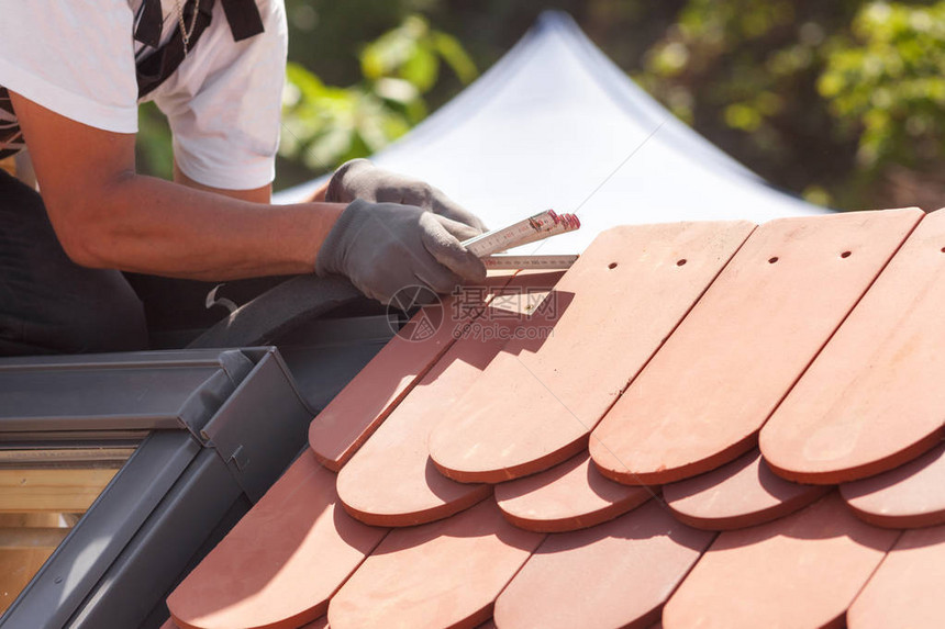 自然屋顶瓷砖的坚硬Roofer建筑工人使用ruller测量瓷图片
