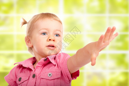 女婴在绿色窗户上伸手去拿东西的肖像图片
