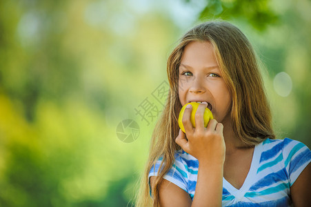美丽的少女咬一个苹果对抗图片