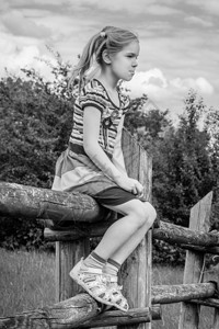 坐在农村木篱上的美丽的悲伤小女孩图片