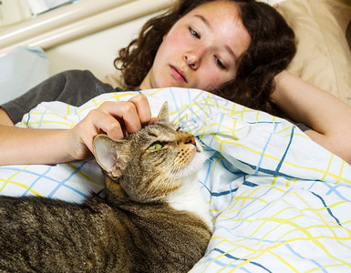 家庭猫和年轻女孩早上醒来时双眼睁开躺在床上的照片图片
