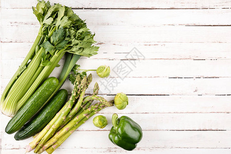 白色木制桌背景的青绿色新鲜季节蔬菜图片