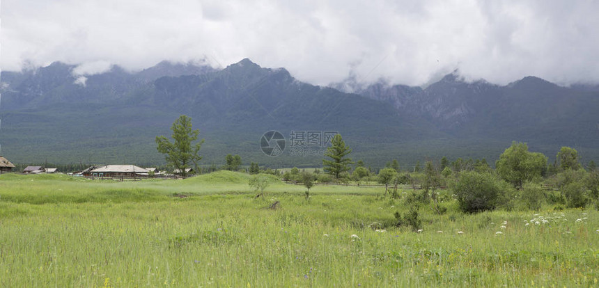 山谷的全景以山为背景的绿色田野的视图乡间小路穿过群山背景的绿色草地图片