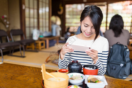 吃饭时用手机拍照的女人图片