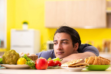 男人在健康食品和不健康食品之间图片