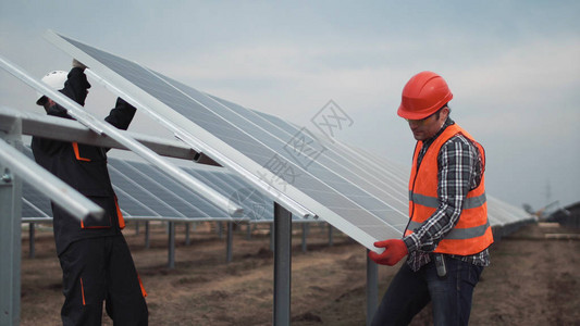 身穿制服和硬件的两名工人在一个太阳能农场用金属安装图片