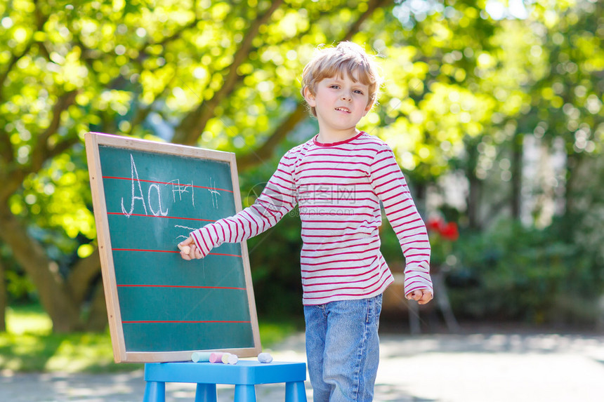 在黑板上练习写字母和数学户外学校或托儿所的金发小孩子和小学生的概念在夏日阳光明媚的日图片