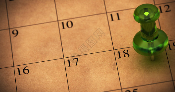 用再生牛皮纸制作的日程表上的绿色图钉图钉指向18号日历上的约会图片