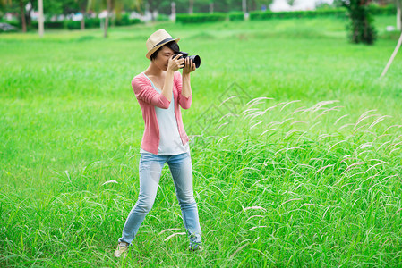 一名年轻女摄影师在公园拍摄照片的影像图片