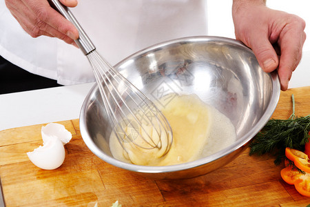 厨师手为煎蛋卷搅拌鸡蛋的图像图片