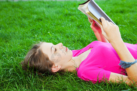 少女看圣经在草地上背景图片