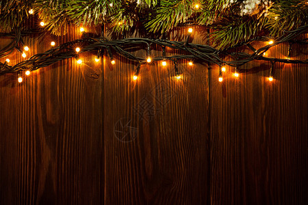 圣诞树枝和木制背景的灯光带图片