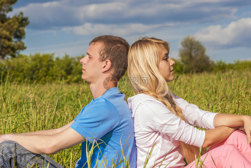 年轻夫妇坐在夏天的绿草上图片