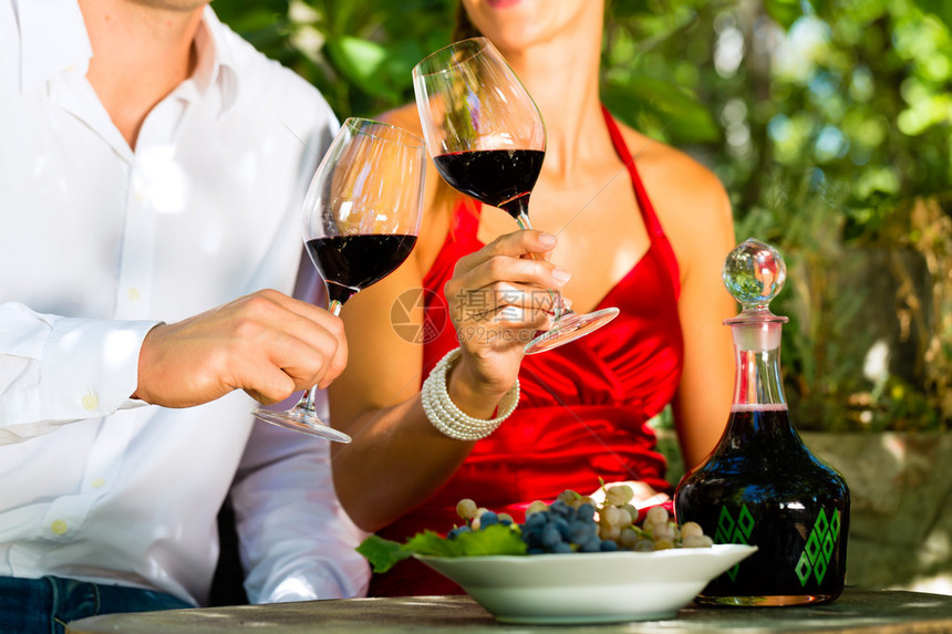 葡萄园里的女人和男人在阳光中喝红酒将图片